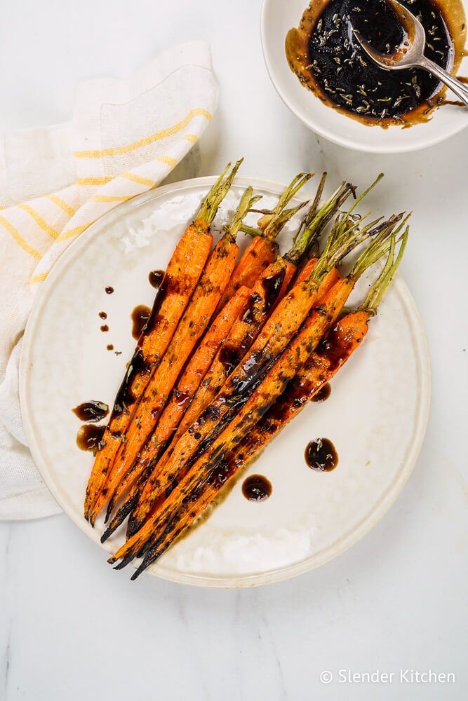 Carrots that were grilled on a plate with balsamic vinegar drizzled on top.