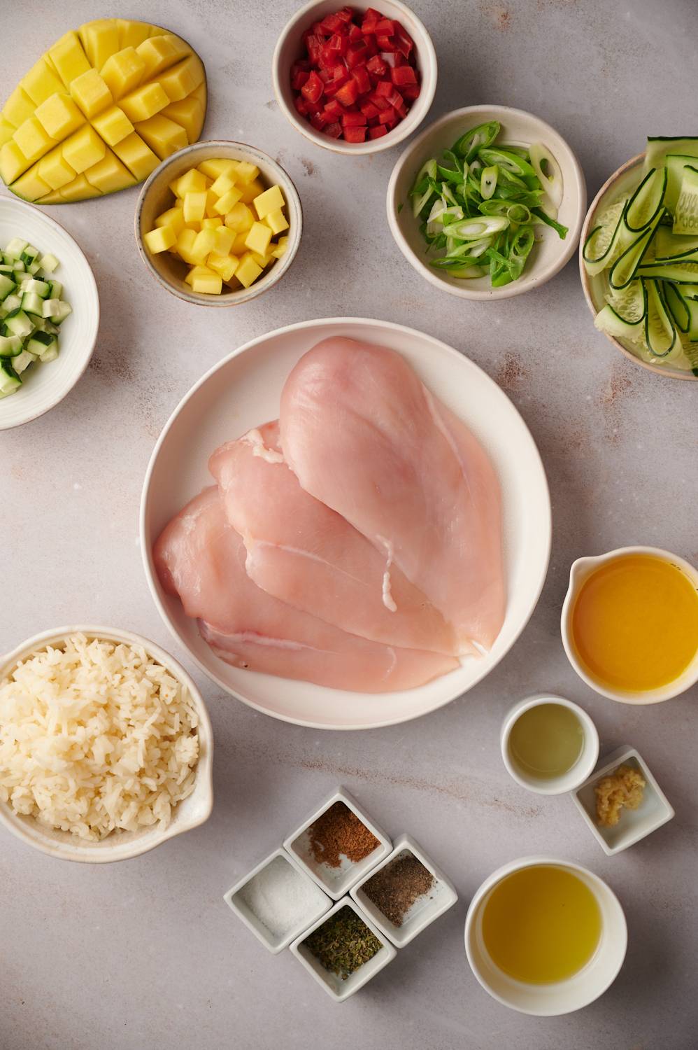 Grilled chicken and rice bowl ingredients including chicken breast, lime, cilantro, mango, red bell pepper, and spices.