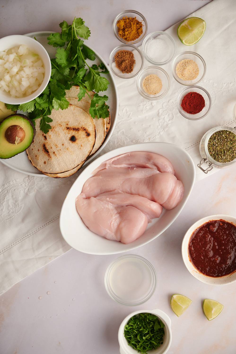 Ingredients for grilled chicken tacos including chicken breast, salsa, taco seasoning, tortillas, and avocado.