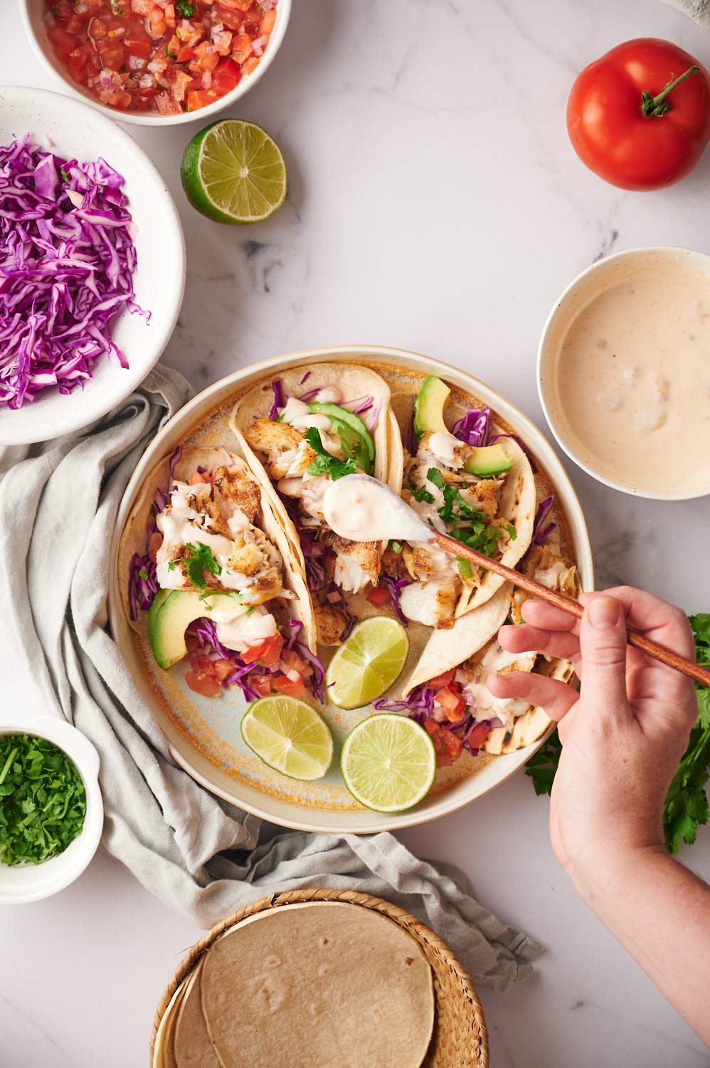 Fish tacos made with grilled cod, tomatoes, cabbage, red onion, and fish sauce.