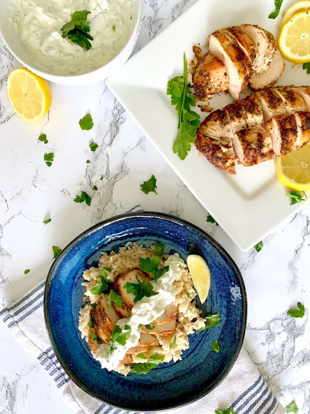 Lemon chicken breast that is grilled with yogurt sauce, rice, and fresh lemons.