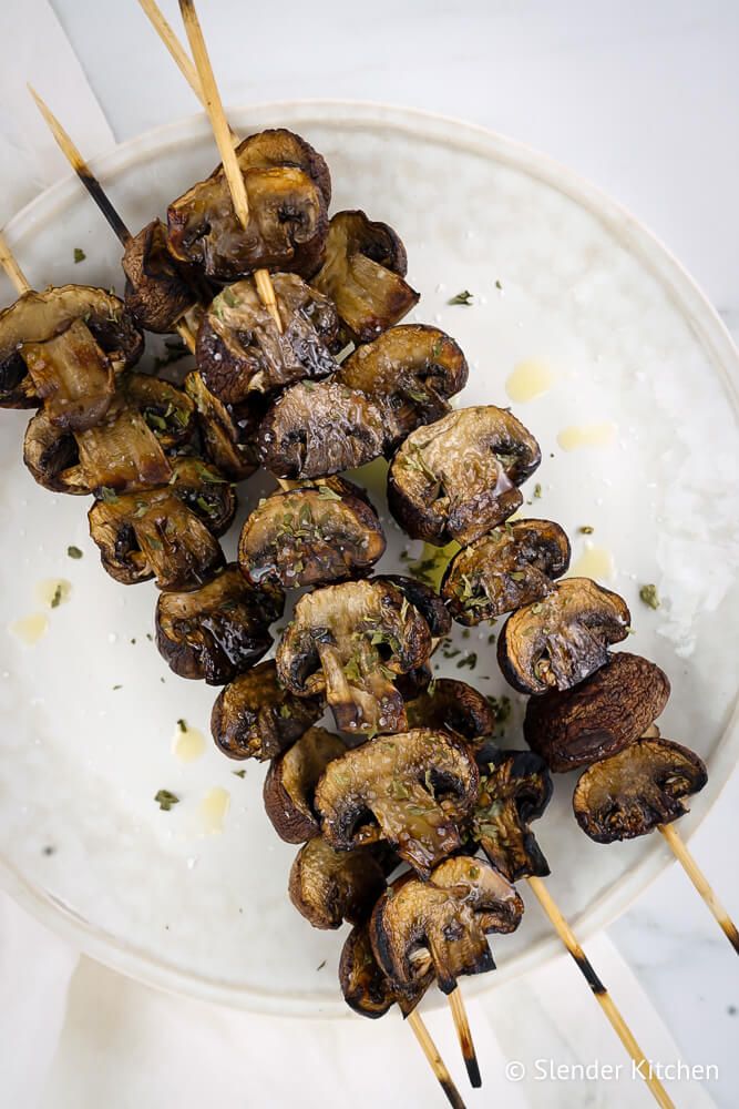 Grilled mushrooms on a wooden skewer with olive oil garlic, balsamic, and parsley.