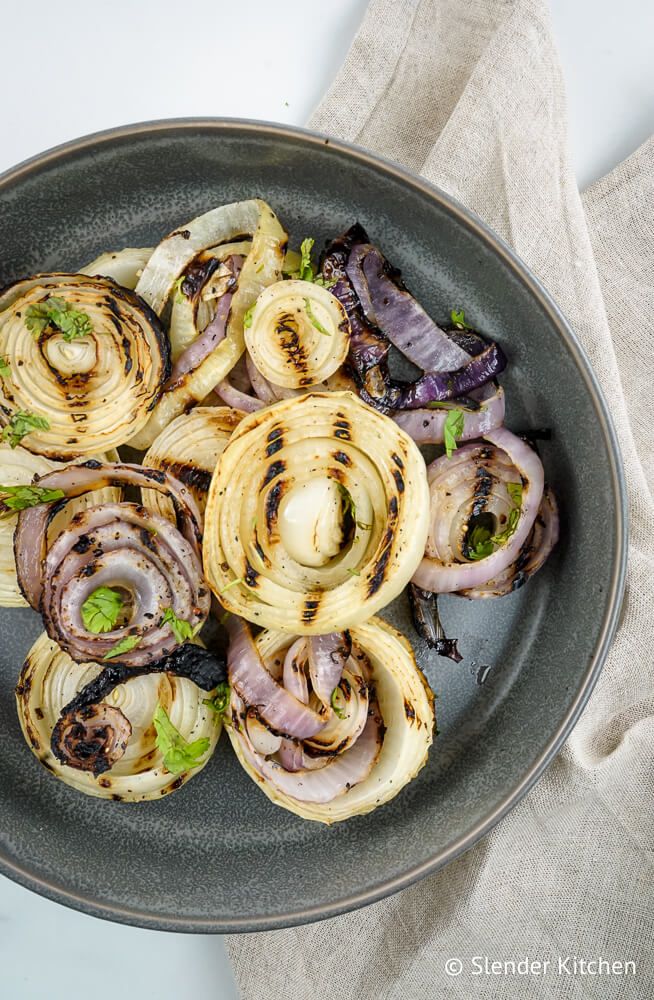 Grilled onions with white onions and red onions with grill marks on a plate.