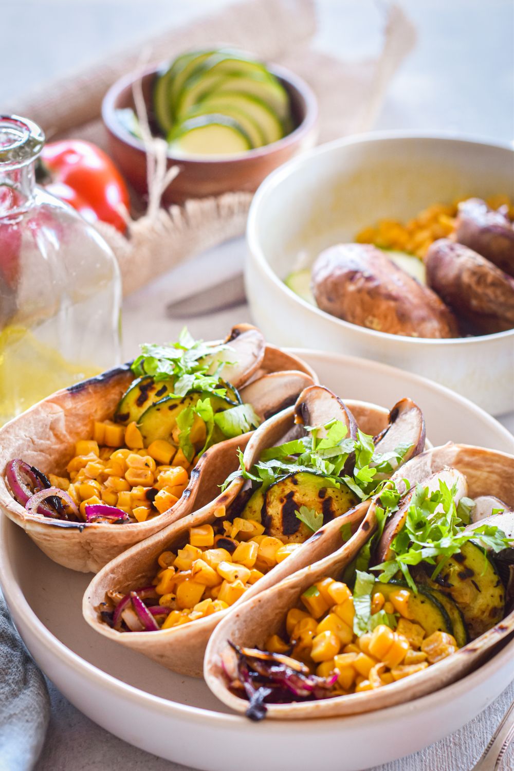 Vegetable tacos with corn, zucchini, and mushrooms in a whole grain tortilla in a white bowl with cilantro.