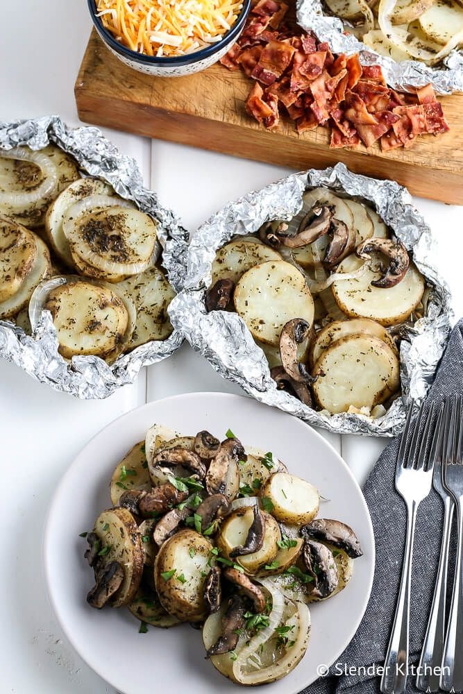 Potatoes cooked on the grill in a foil packet with onions, mushrooms, cheese, and bacon bits. 