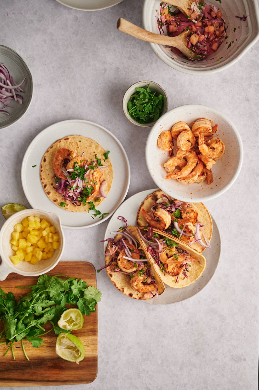 Shrimp tacos with grilled shrimp, pineapple cabbage slaw, and cilantro on corn tortillas.