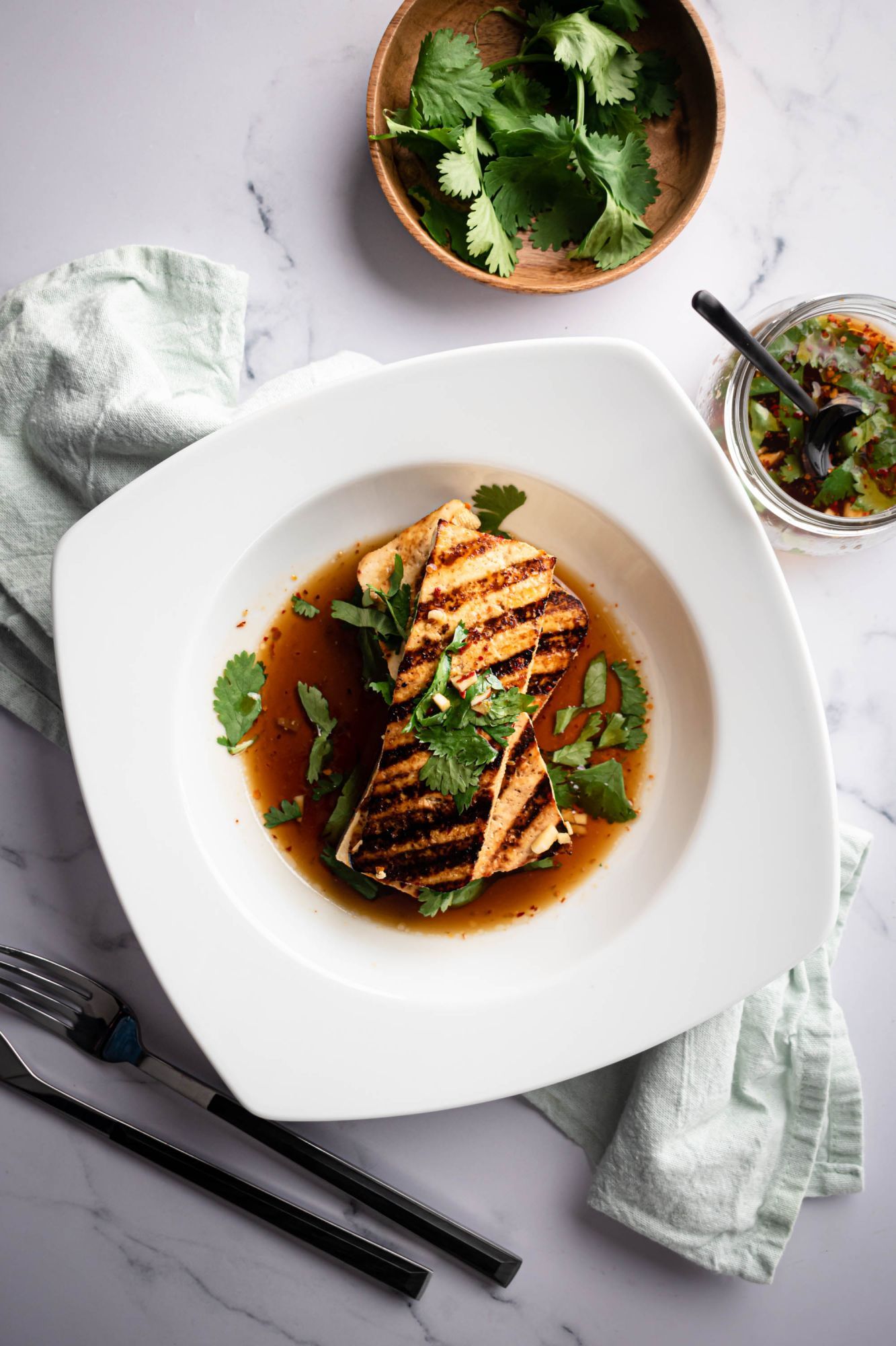 Crispy grilled tofu with dark grill marks drizzled with a cilantro soy sauce.