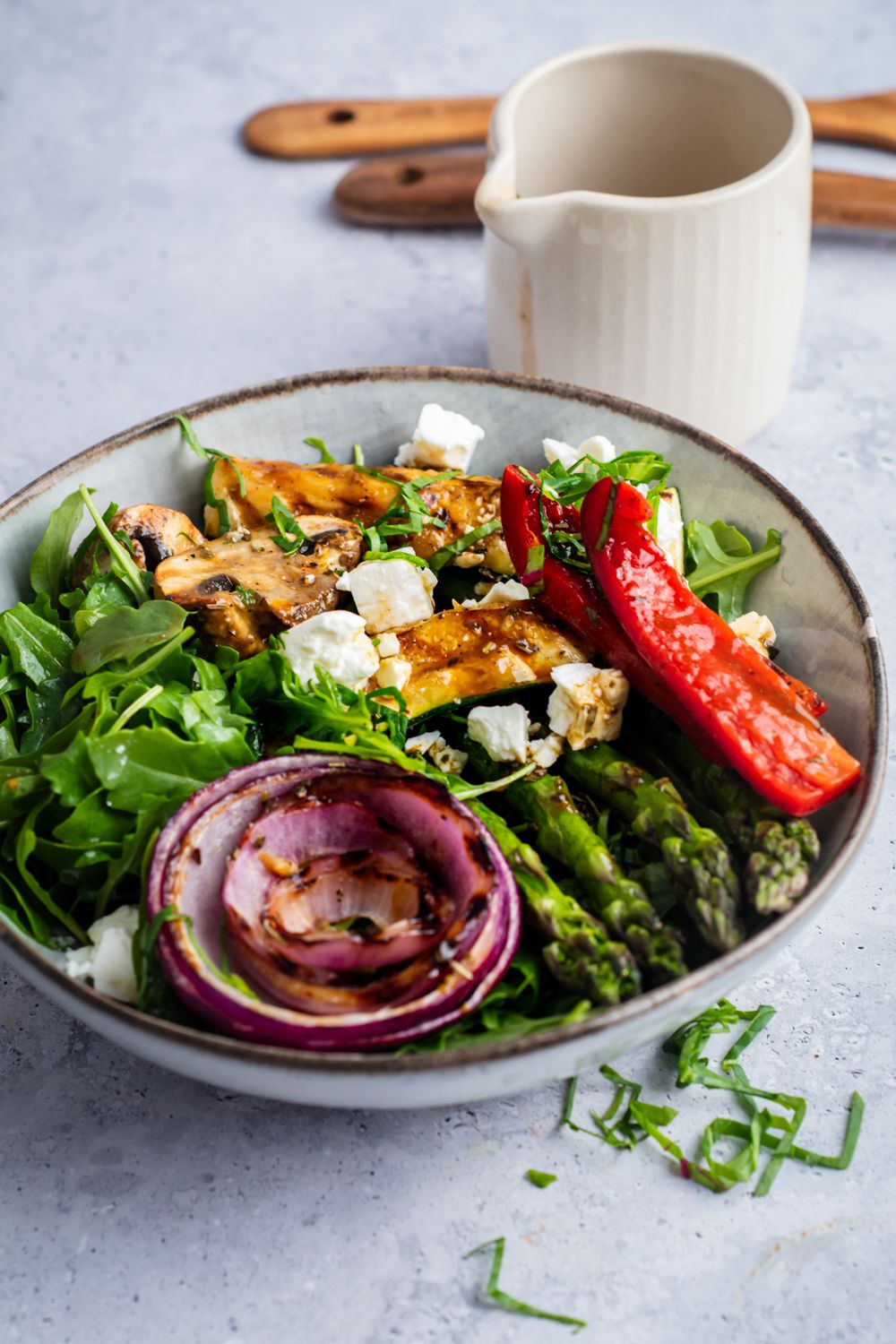 Grilled veggie salad with arugula, feta cheese, fresh basil, and grilled vegetables in balsamic vinaigrette.