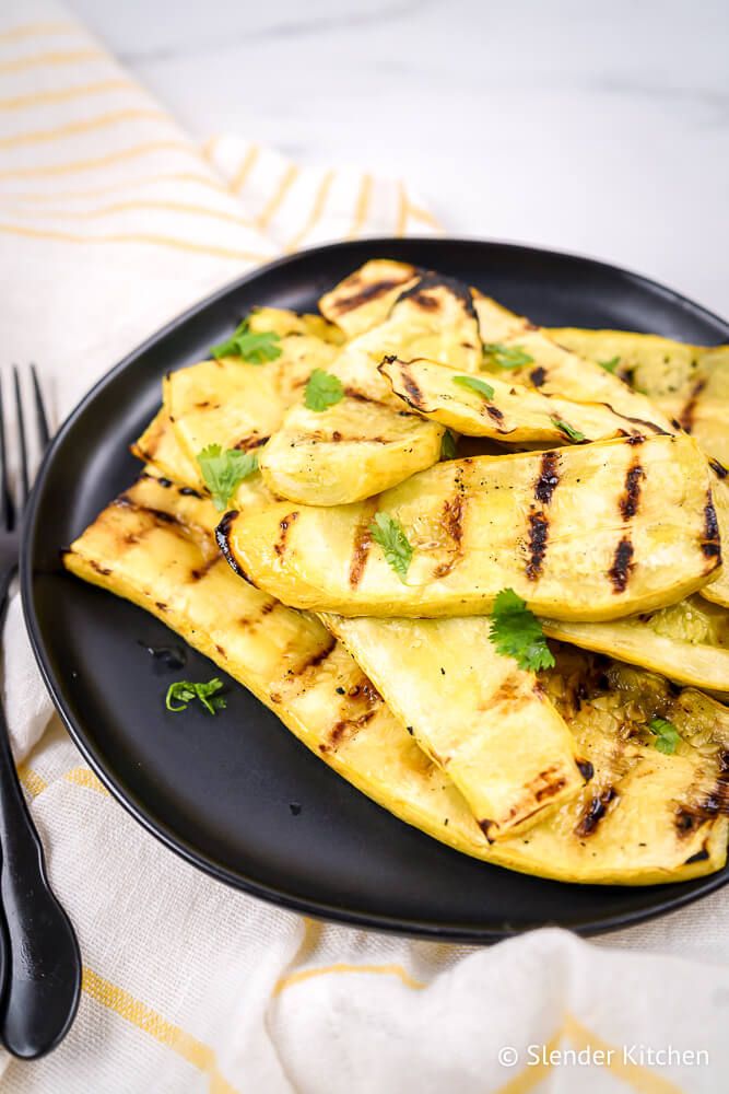 Grilled yellow summer squash with grill marks on a plate with a yellow napkin.