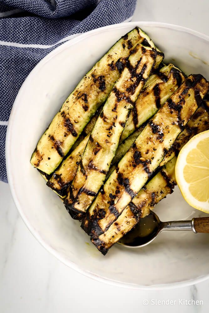 Grill zucchini spears on a white plate with a blue napkin.