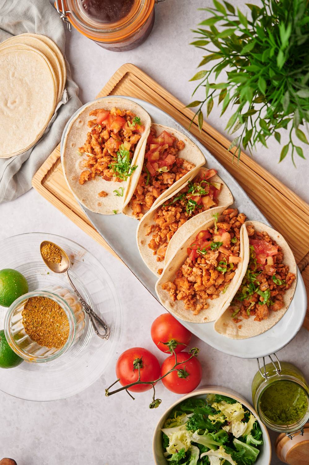 Chicken tacos with ground chicken, tomatoes, cilantro, lettuce, and corn tortillas on a plate.