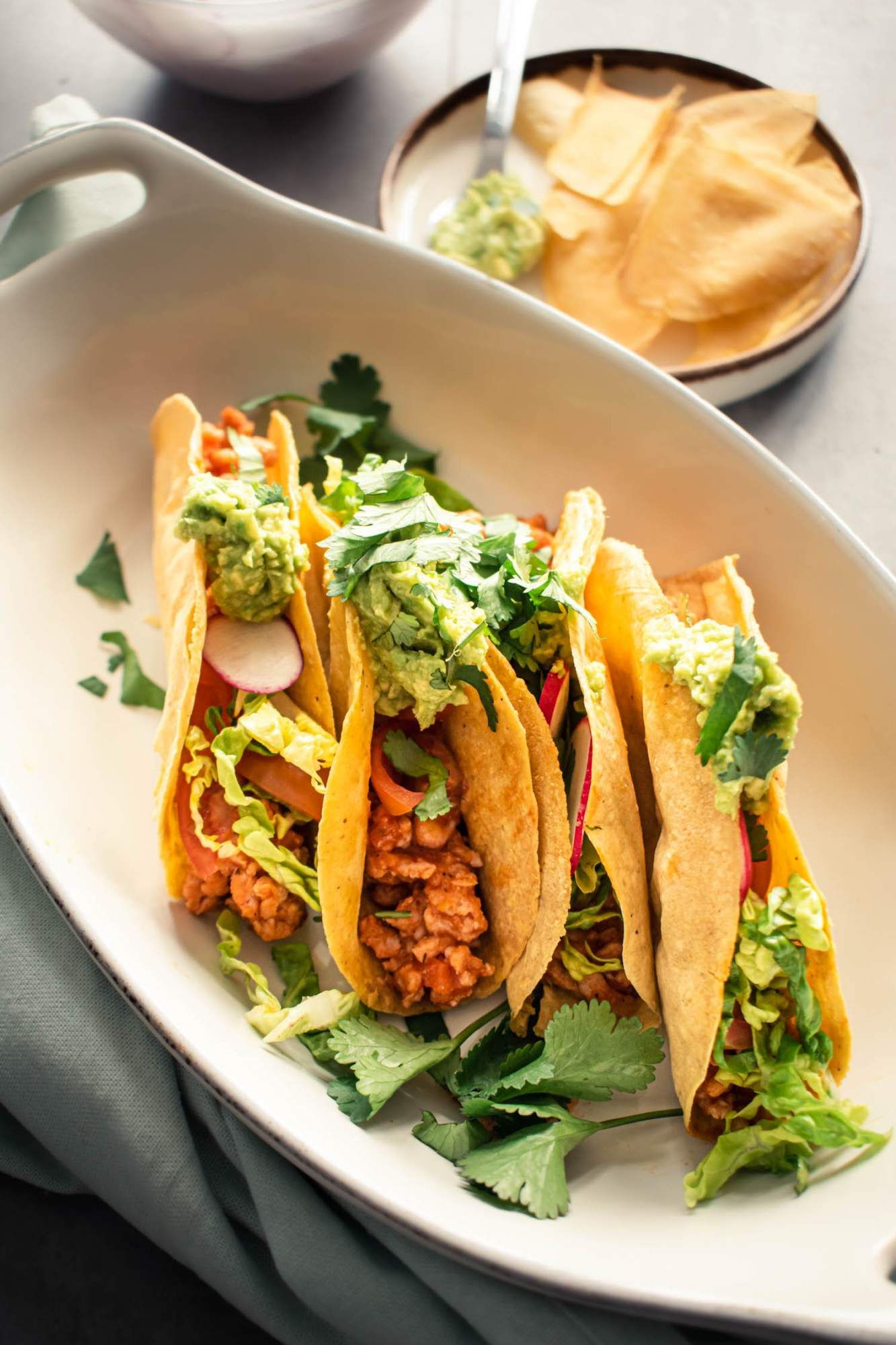 Tacos with ground turkey meat in baked crispy taco shells with guacamole, salsa, cilantro, and radishes on top.