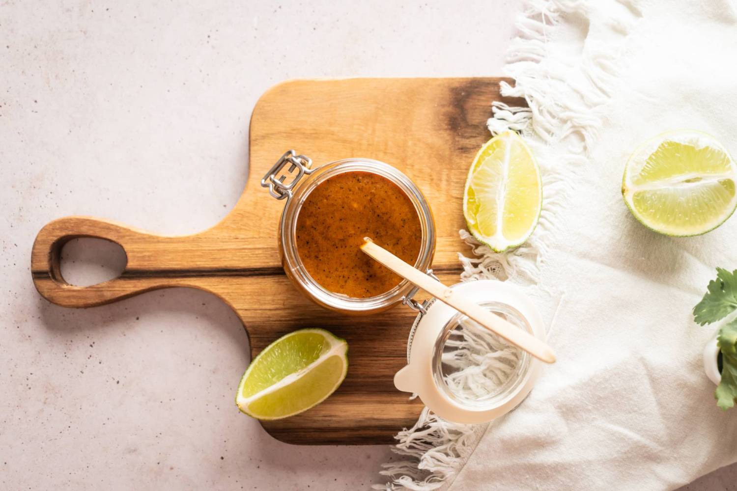 Spicy salsa with habanero, lime juice, orange juice, garlic, and tomatillos in a jar on a cutting board.