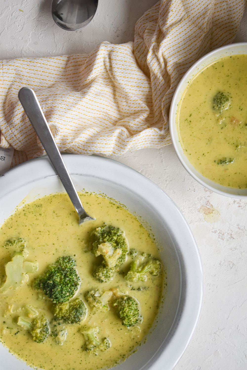 Soup with broccoli and cheese in two bowls  with broccoli florets on top. 