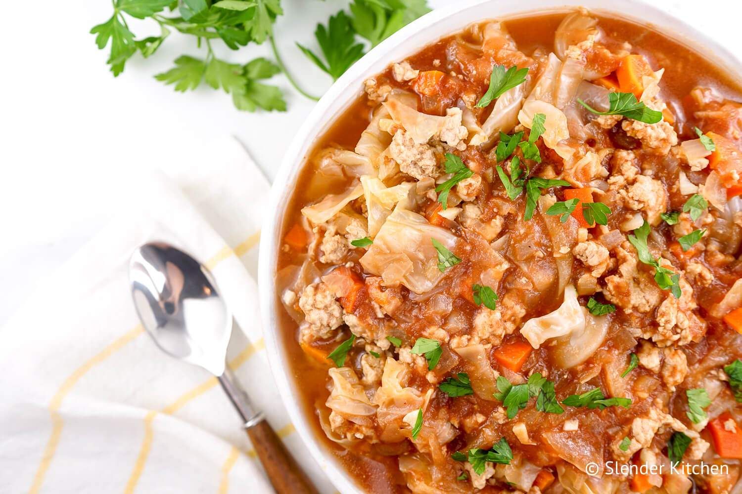 Turkey and cabbage soup made with ground turkey, green cabbage, and tomatoes in a bowl with parlsey,