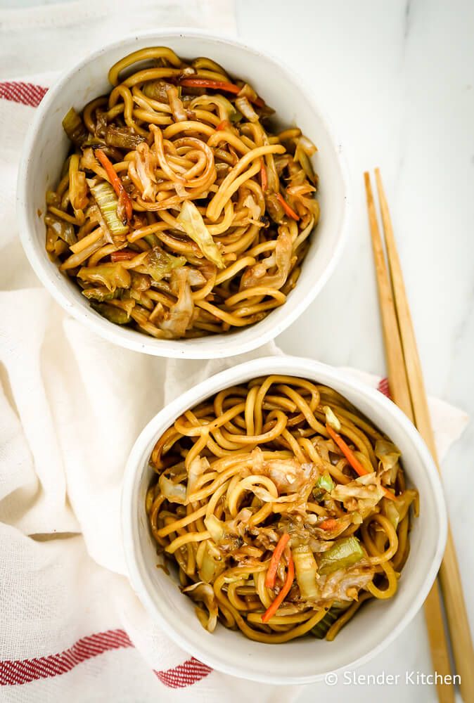 Healthy chow mein with noodles, cabbage, celery, and carrots in two bowls.