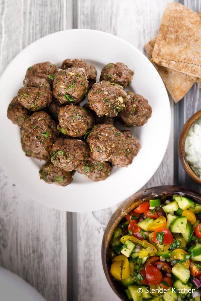 Keftedes Greek meatballs on a plate with tomato and cucumber salad and pita bread.