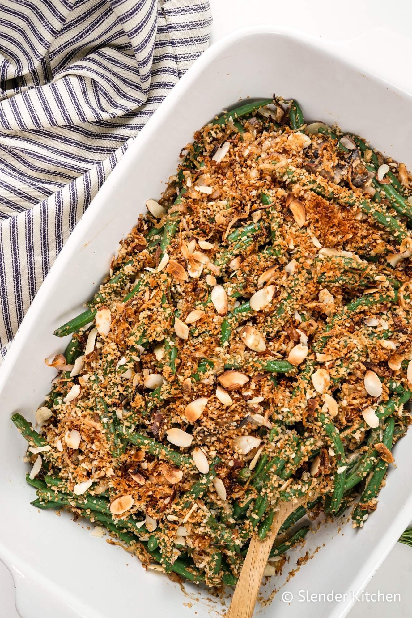 Lighter green bean casserole with cripsy onions, fresh green beans, and mushroom sauce in a white baking dish. 