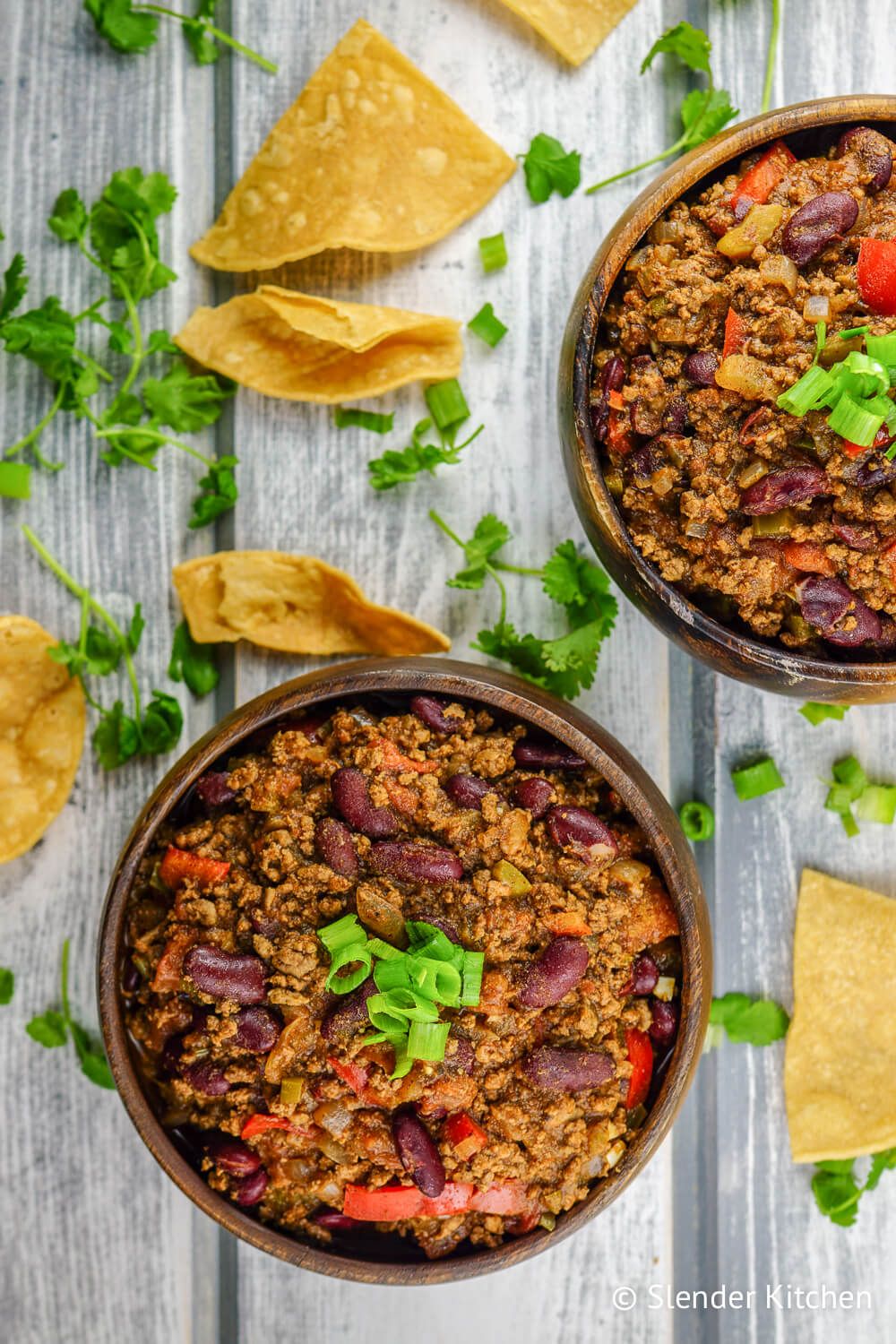 Ground turkey chili in a wooden bowl with cilantro and cheese.