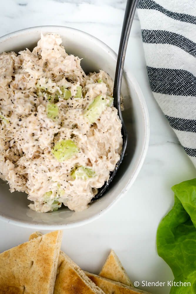 Tuna salad with Greek yogurt and celery in a bowl with a black spoon.