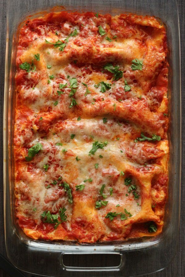 Zucchini lasagna with marinara sauce, noodles, and melted cheese in a baking dish with basil on top.