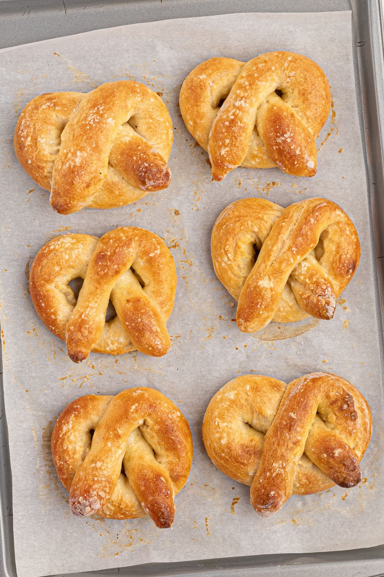 Baked homemade soft pretzels on a baking sheet covered with parchment paper.