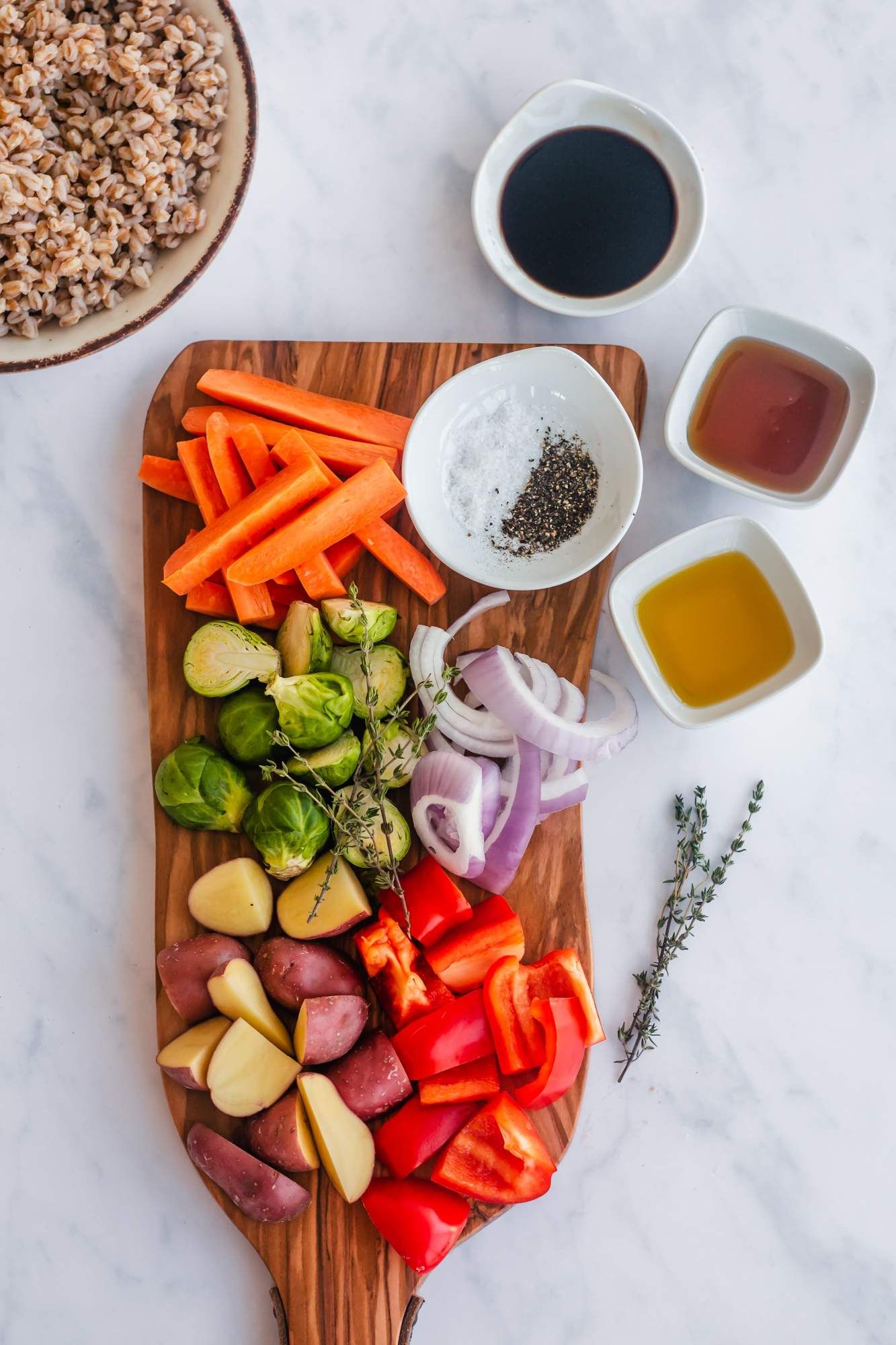 Ingredients for roasted vegetable bowls including Brussels sprouts, potatoes, peppers, onions, and farro.