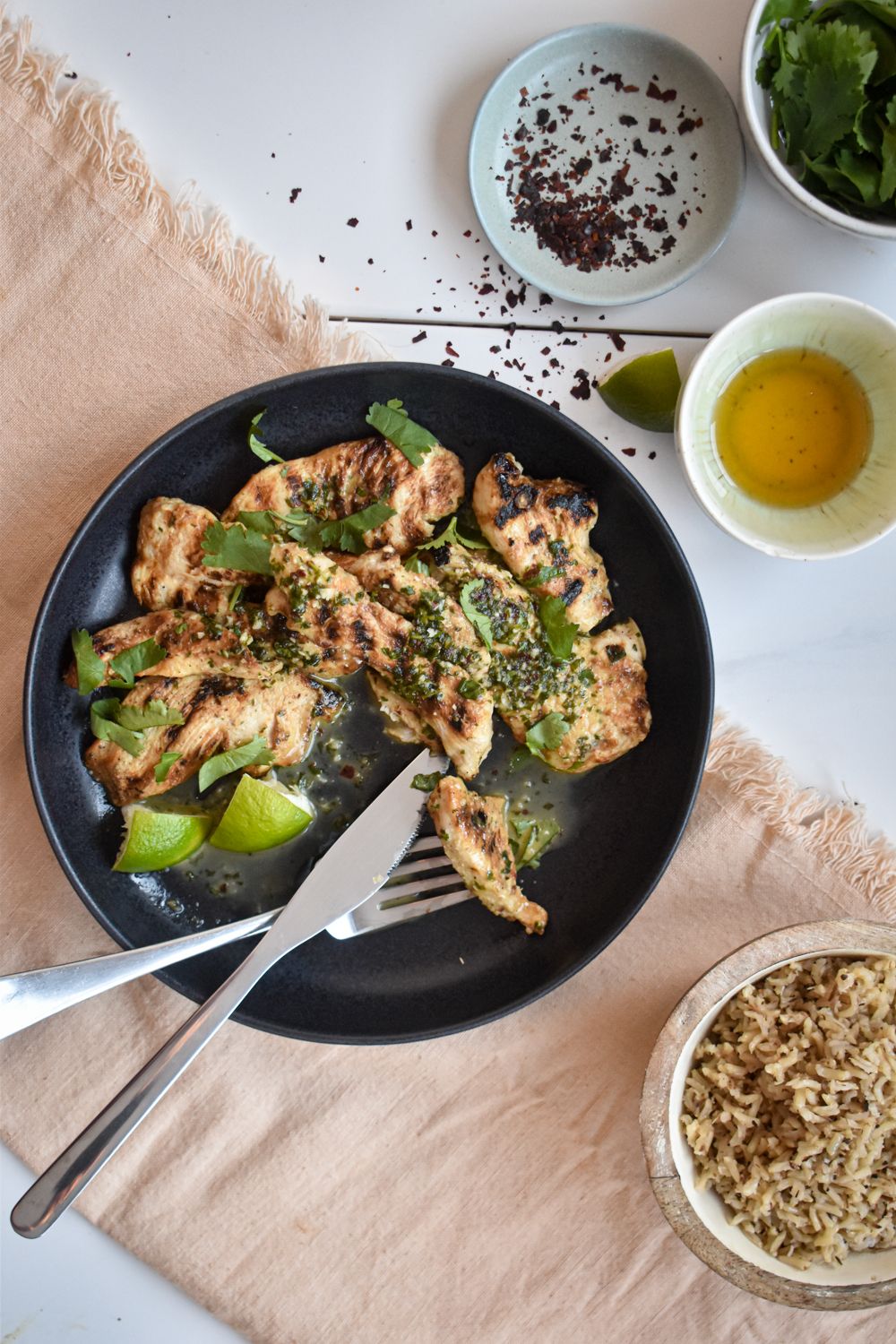 Honey lime chicken breast on a black plate with a knife and fork. 