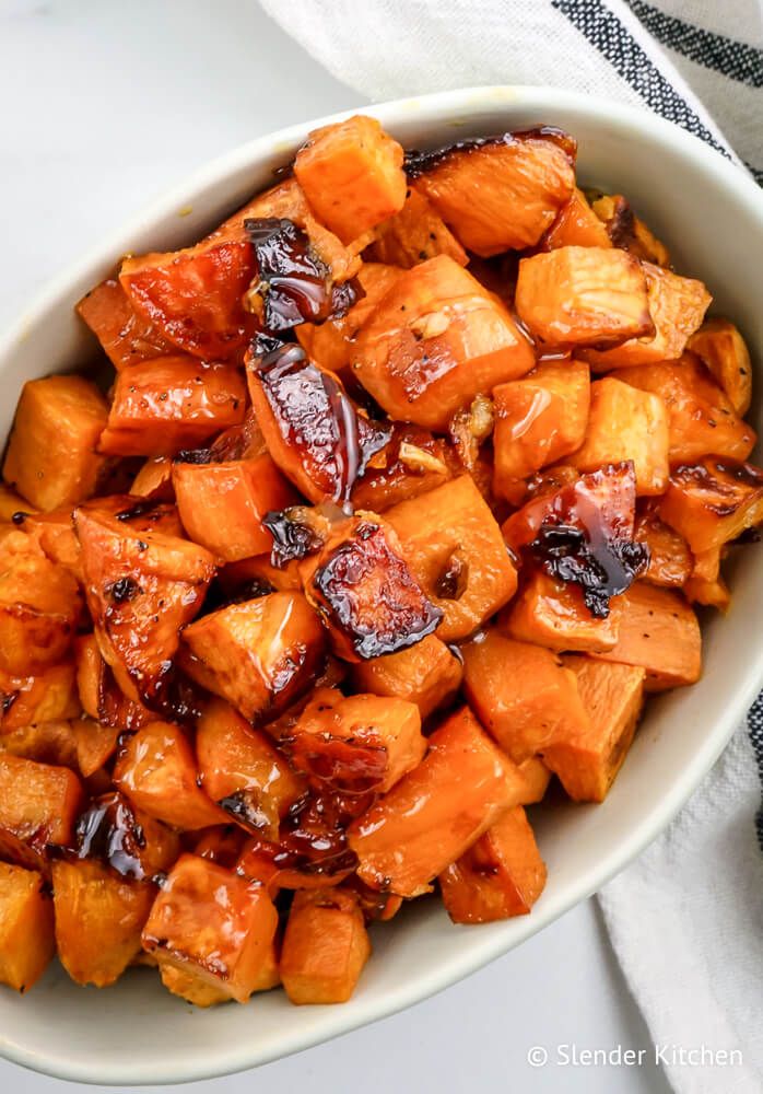 Roasted sweet potatoes with honey in a dish with a white napkin on the side.