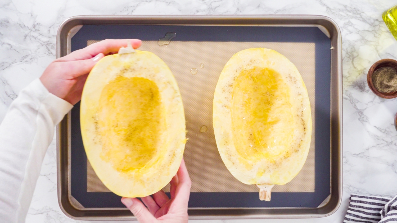 Spaghetti squash on a baking sheet with olive oil, salt, and pepper.