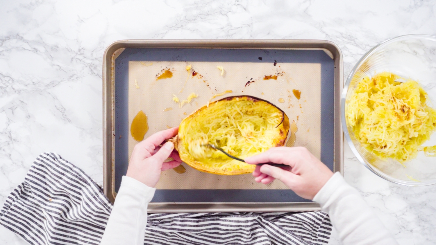 Spaghetti squash strands being removed from a roasted squash.