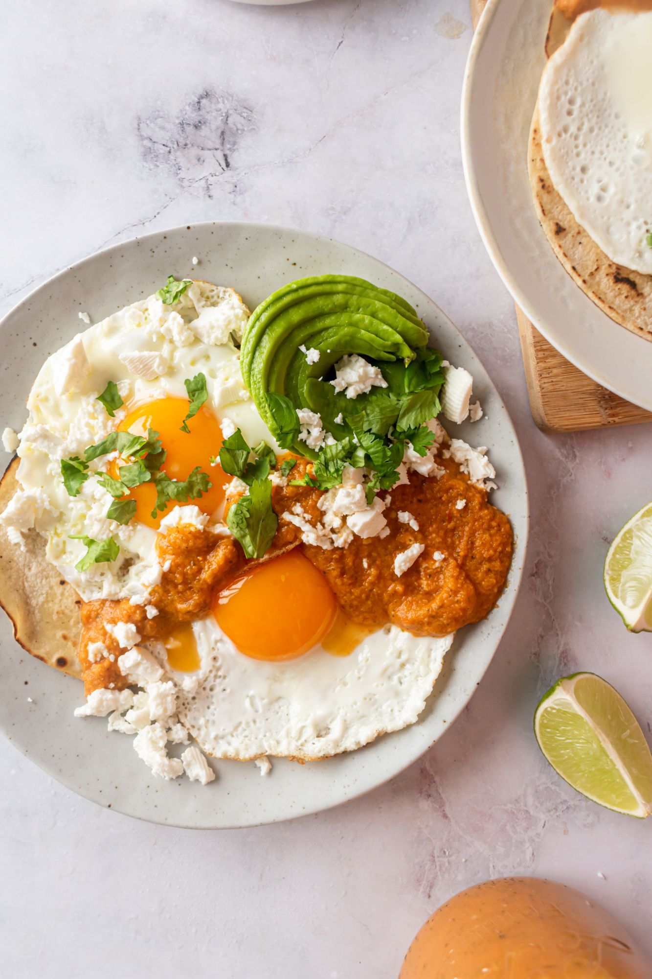 Mexican huevos rancheros with sunny side up eggs covered in ranchero sauce on corn tortillas with cilantro.