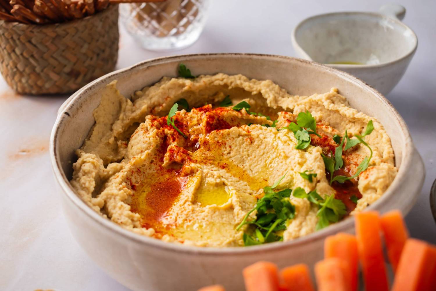 Bowl of homemade hummus with paprika, olive oil, and parsley.