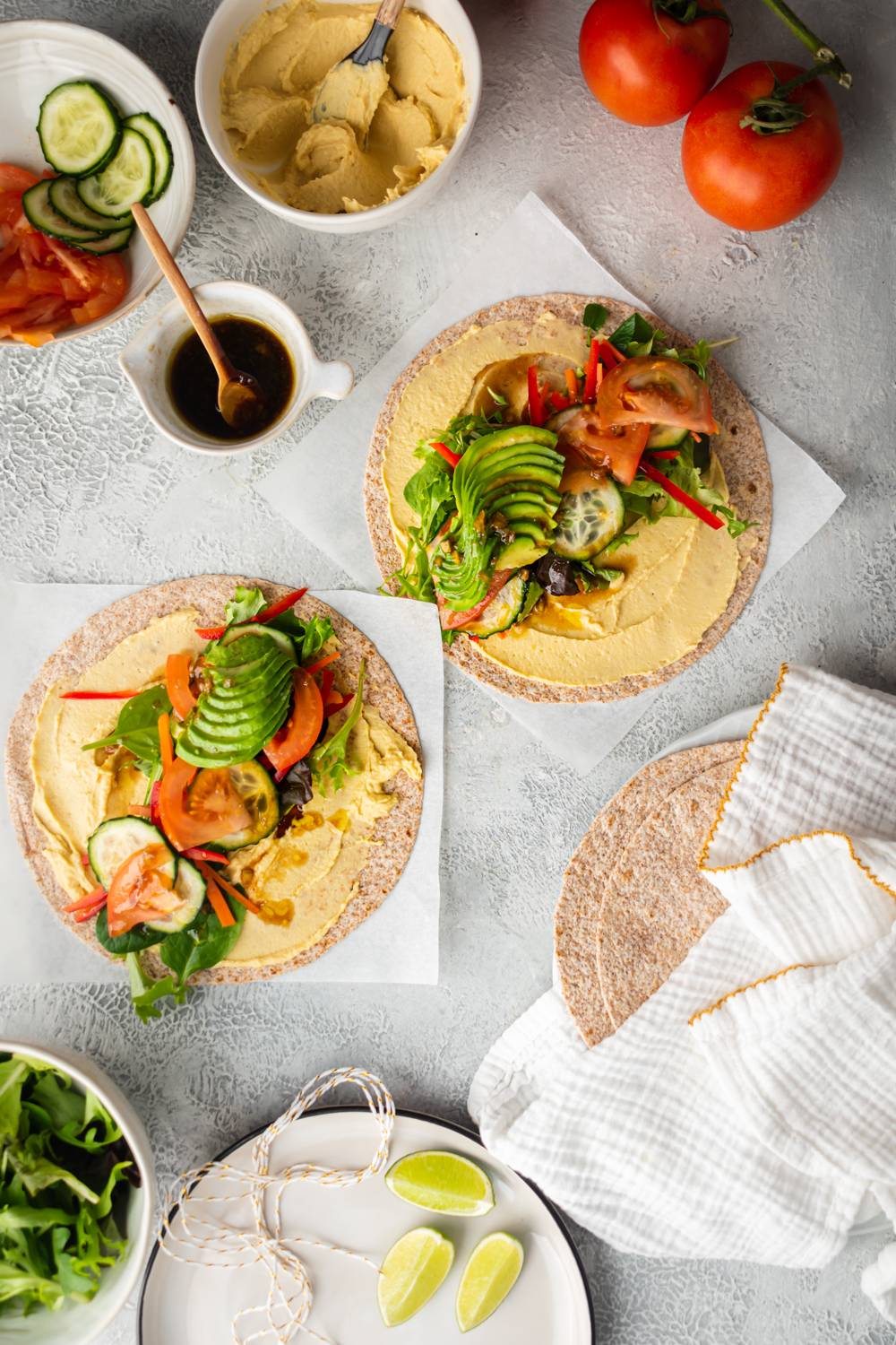 Vegetable hummus wraps on whole grain tortillas with tomatoes, cucumbers, greens, hummus, and avocado.