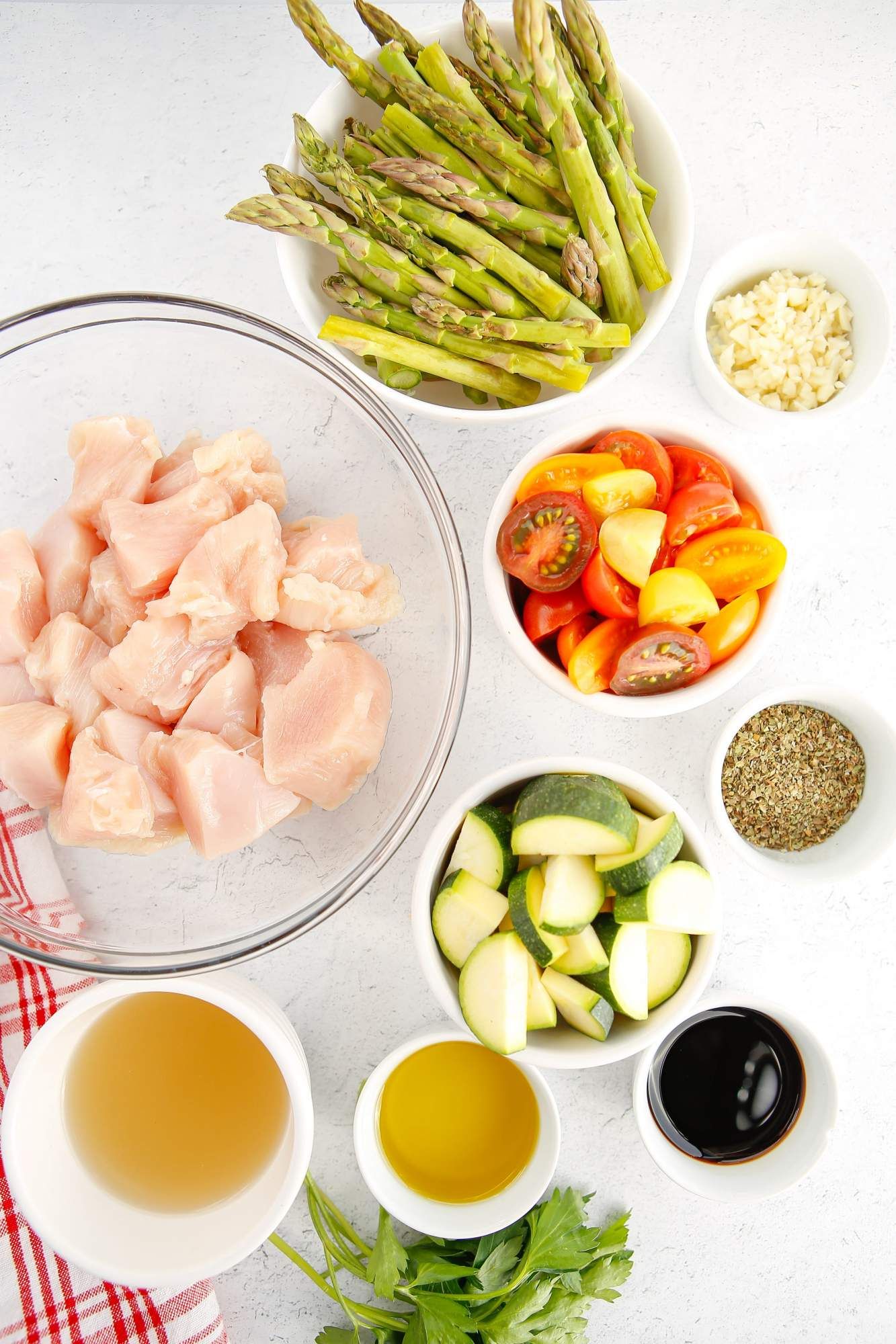 Italian chicken ingredients including asparagus, tomatoes, garlic, zucchini, balsamic vinegar, and spices.