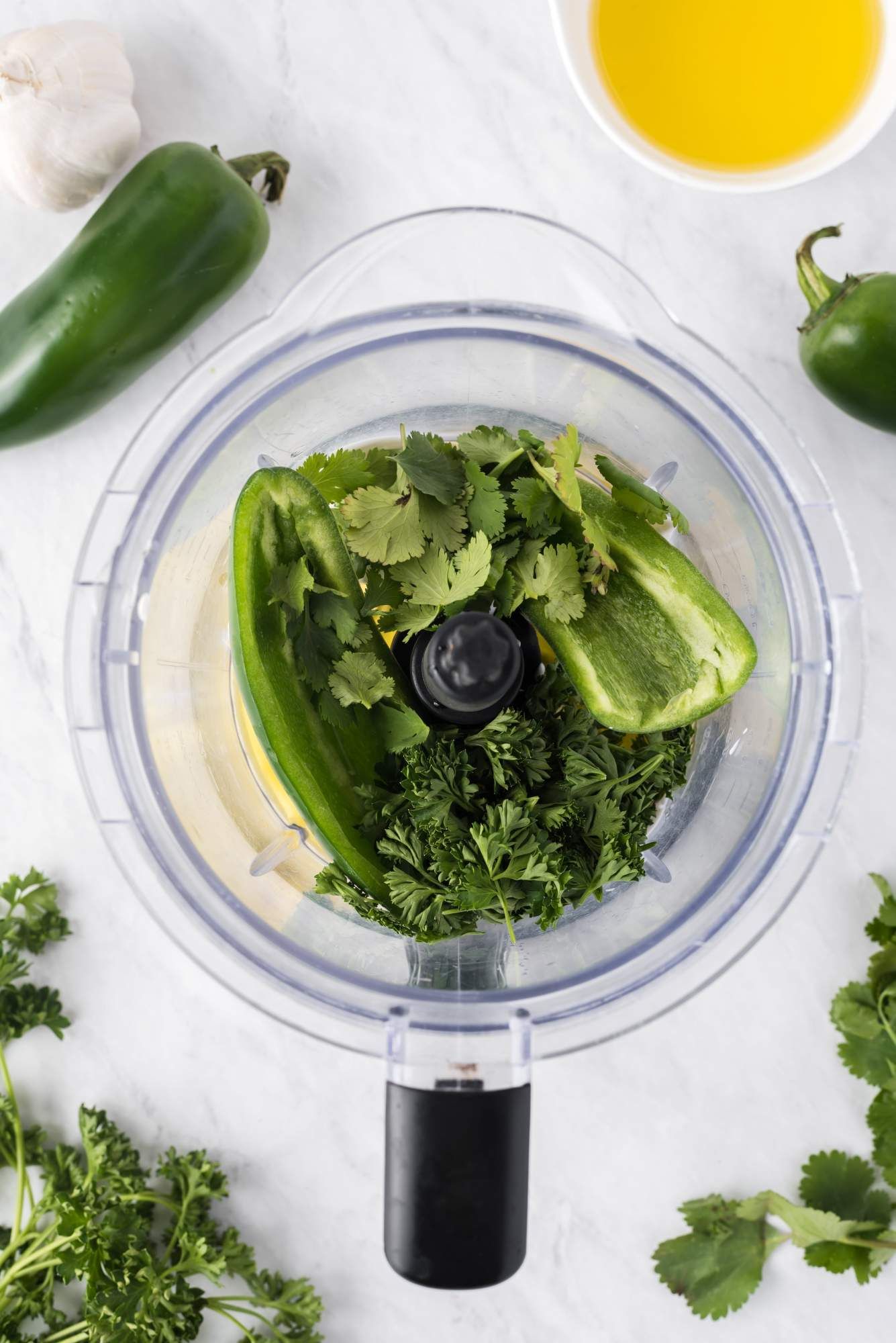 Ranch dressing with jalapenos being made in a food processor with jalapenos, herbs, yogurt, oil. vinegar, and dill.