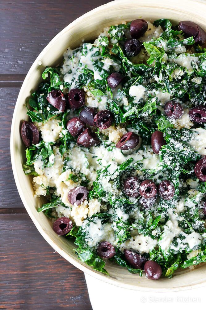 Caesar quinoa bowls with kale in a bowl with black olives, chopped kale, quinoa, pine nuts, and Parmesan cheese.