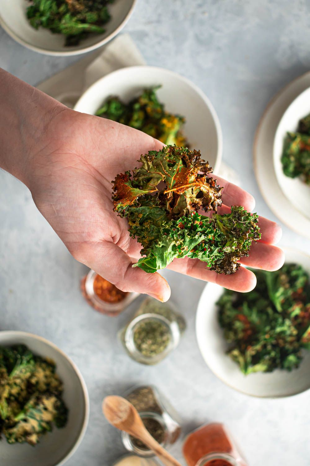 Crispy kale chips with paprika and garlic being held in a hand.