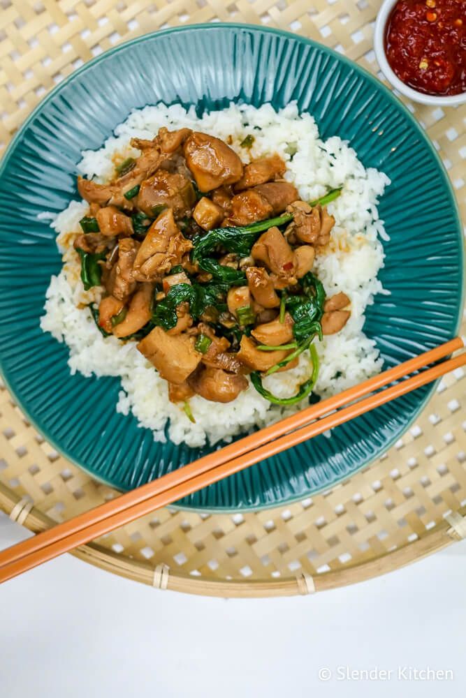 Korean chicken thighs with white rice and spinach on a blue plate with chopsticks.