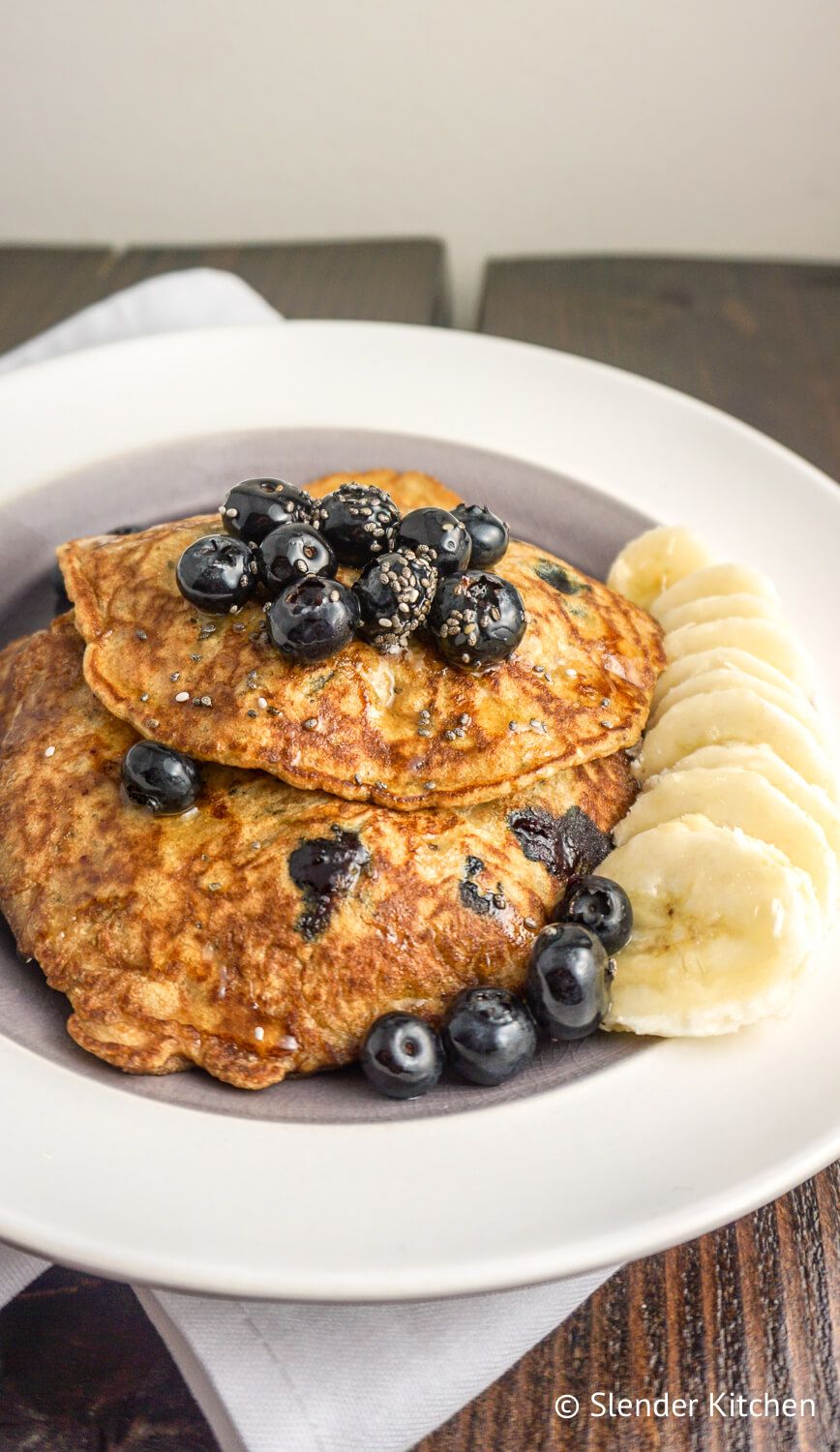 Chia seed pancakes with blueberries and bananas on a white plate.