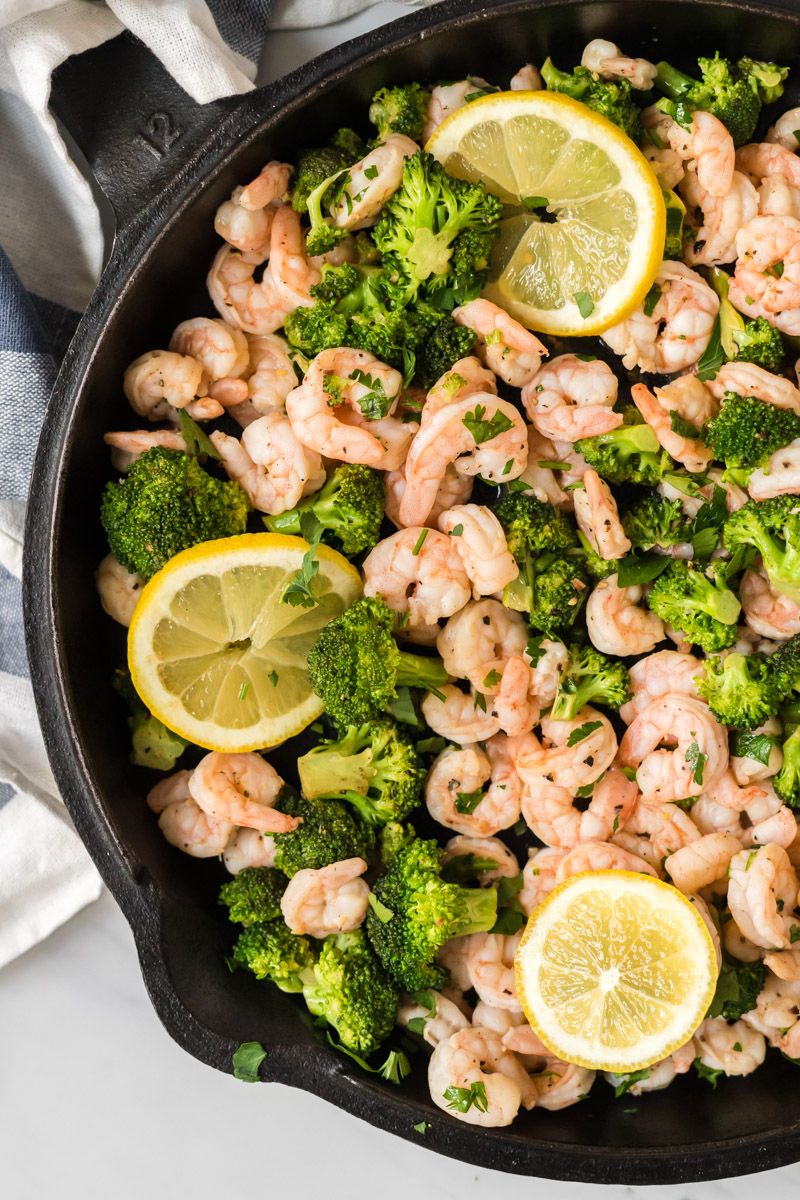 Shrimp and broccoli tossed with lemon pepper seasoning cooked in a skillet with a napkin on the side.