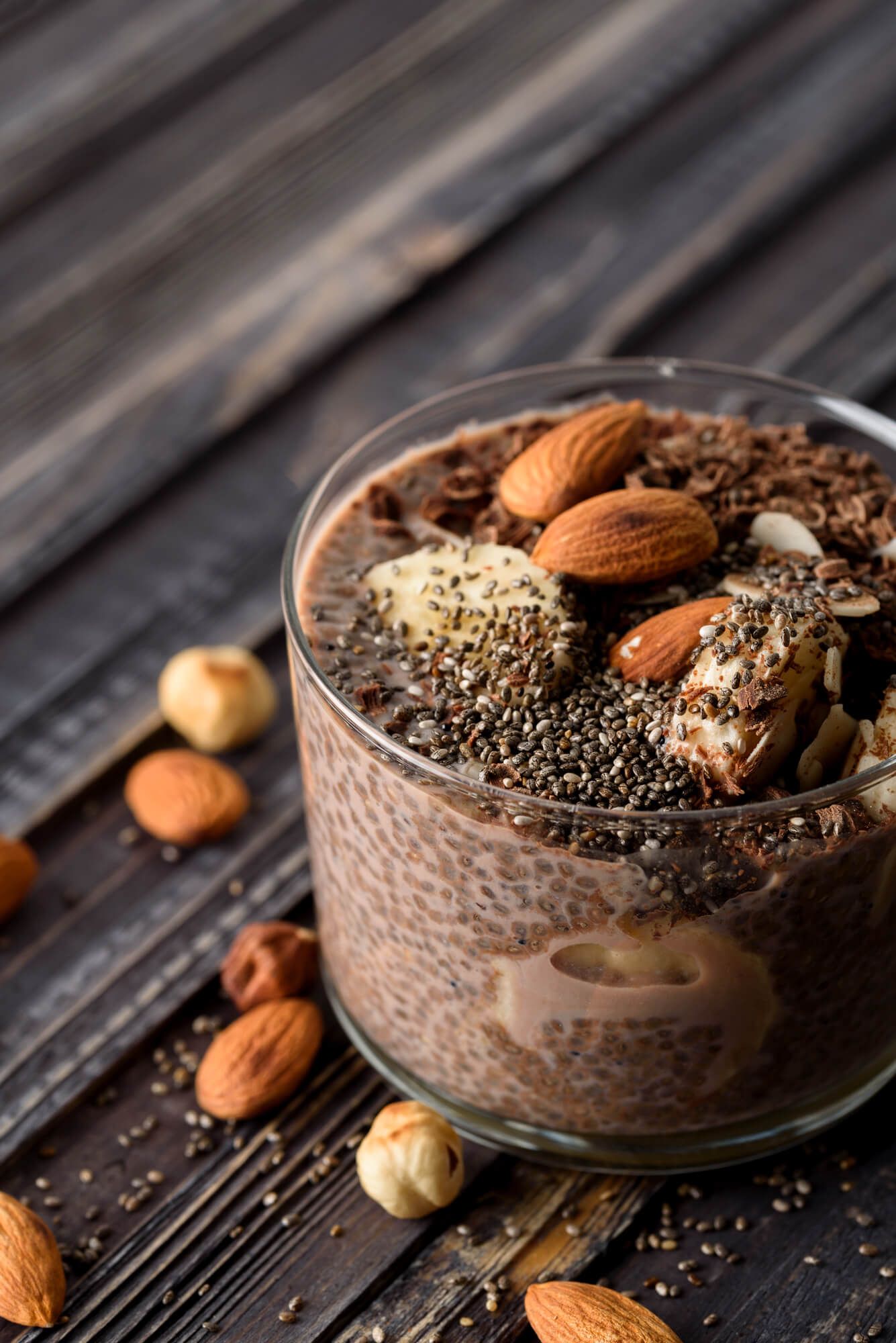 Low carb chocolate chia pudding in a glass with almonds and chocolate shavings.