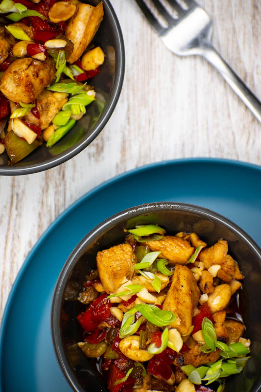 Paleo kung pao chicken with a savory sauce, red peppers, peanuts, and sliced onions.