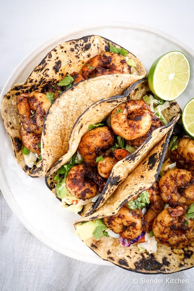 Keto shrimp tacos with cabbage avocado slaw, low carb tortillas, and lime.