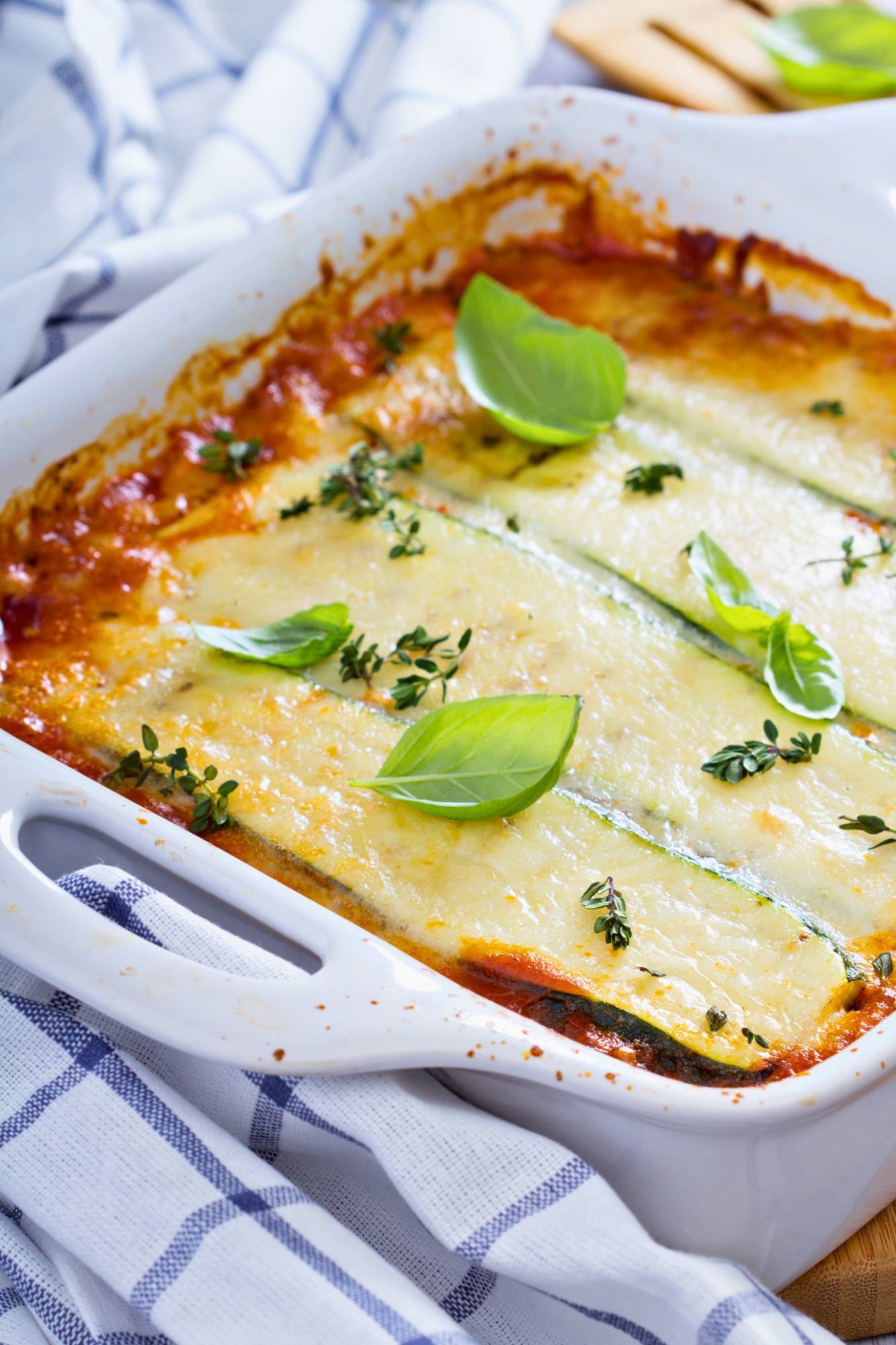 Keto zucchini lasagna with layers of zucchini, cottage cheese, turkey, and marinara sauce baked in a dish with fresh basil.