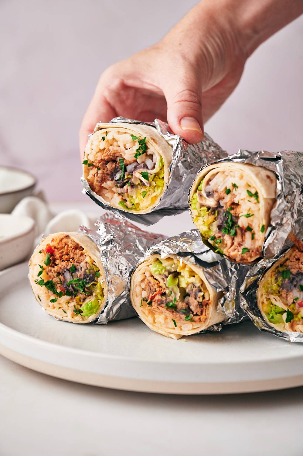 Mexican machaca burritos with flour tortillas, rice, beans, lettuce, cilantro, and cheese on a plate.