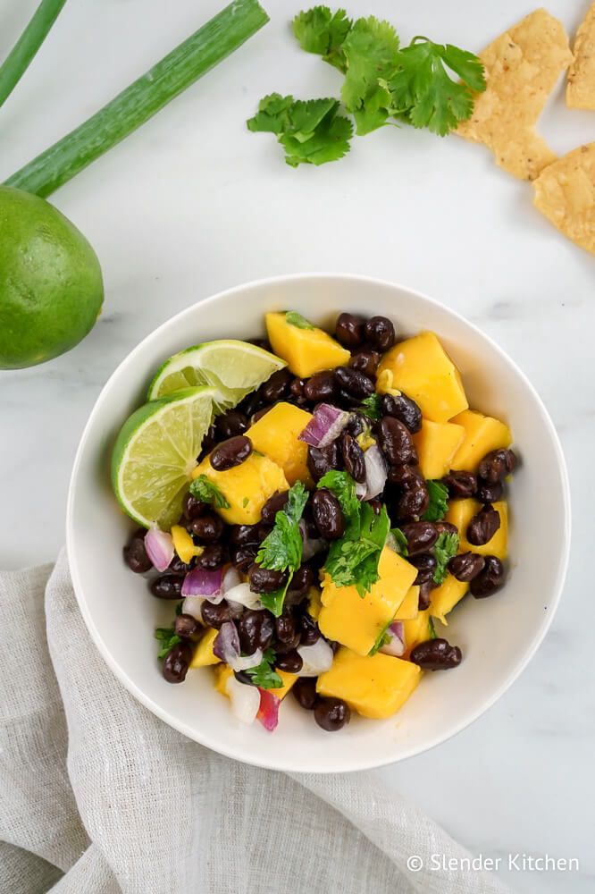 Mango salsa with mango, black beans, cilantro, lime juice, and red onions in a bowl.