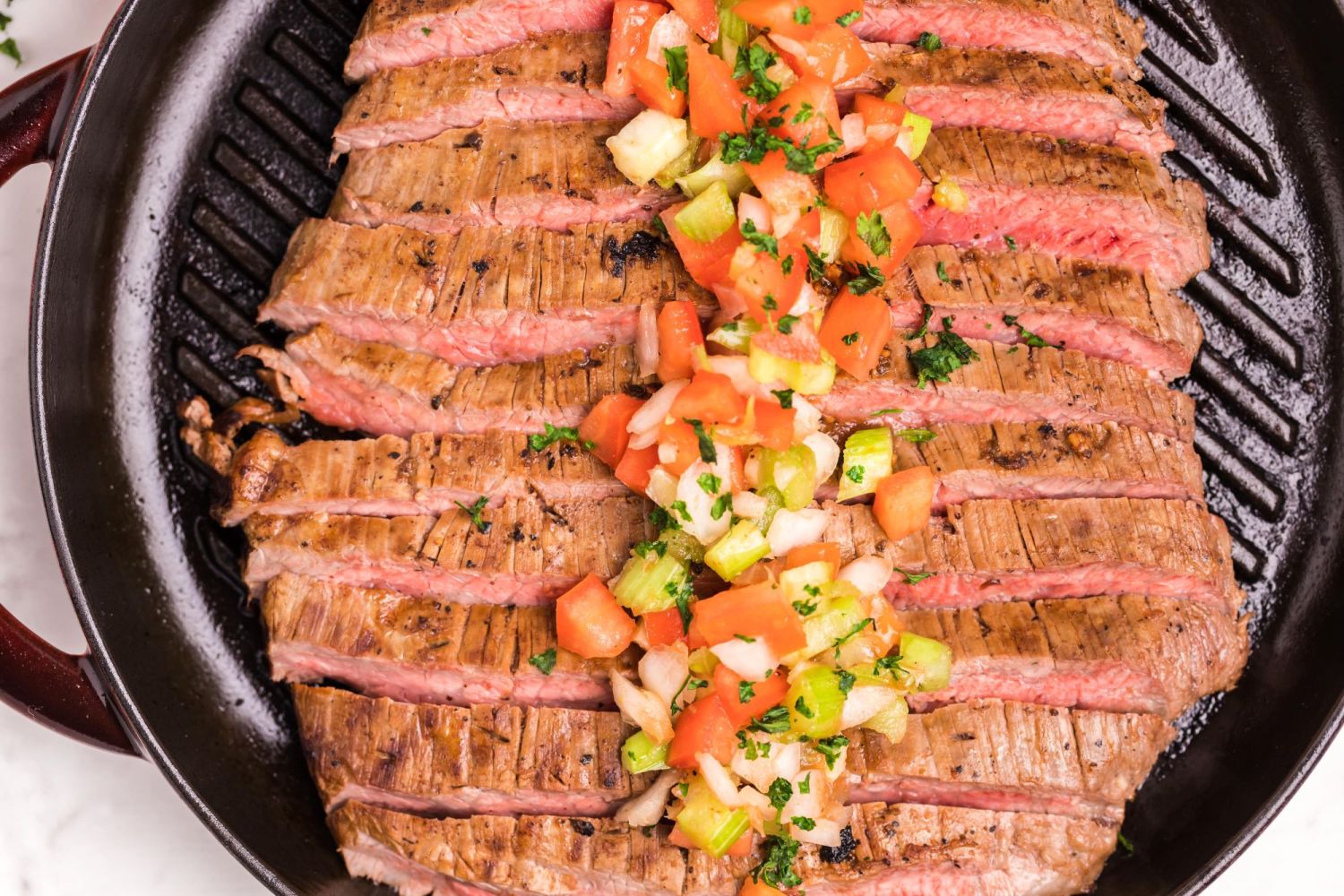 Grilled flank steak with bloody mary in a grill plan with tomato and onion salsa.