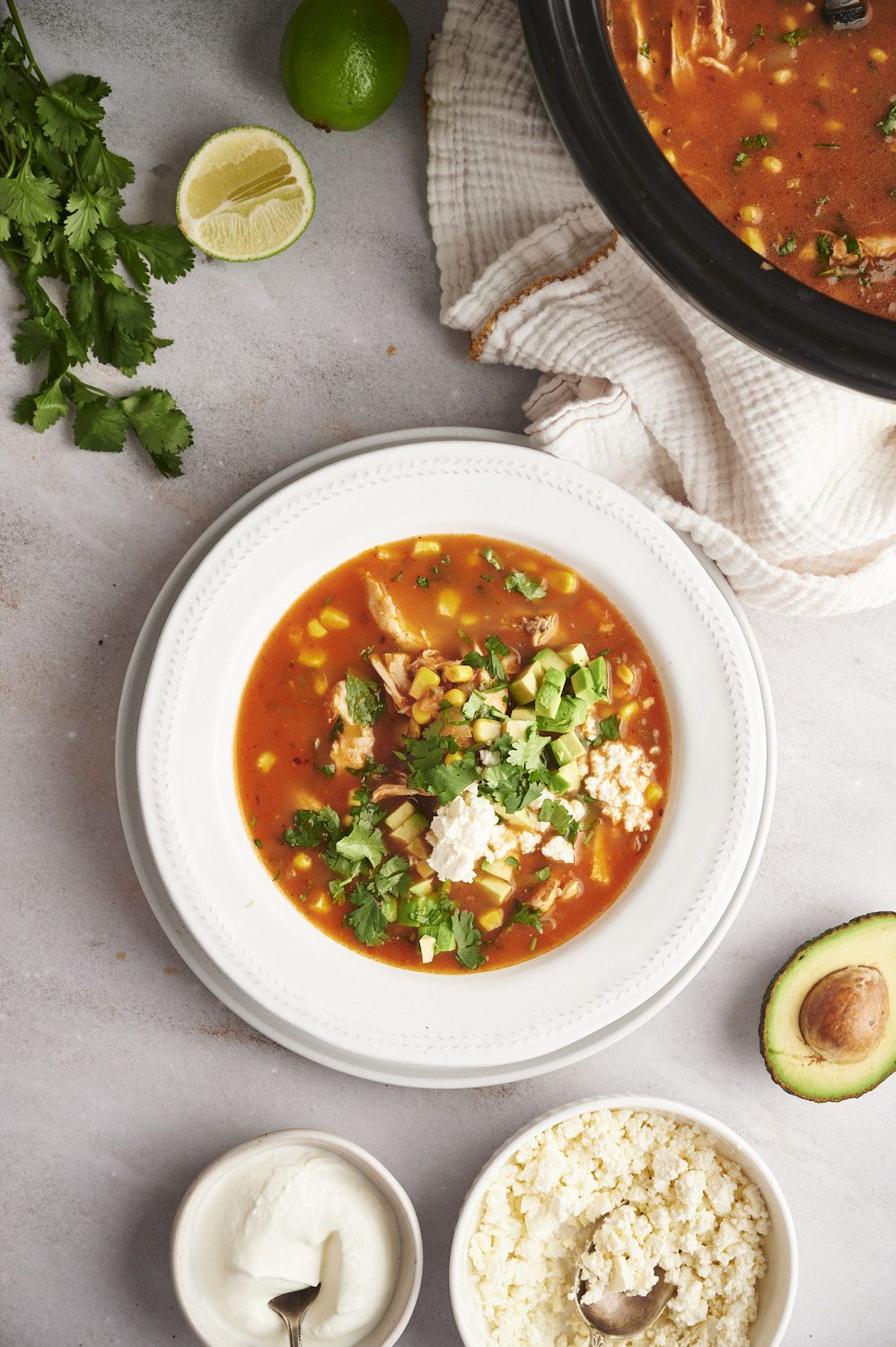 Mexican style chicken soup with shredded chicken, cilantro, corn, and avocado in a spicy tomato broth.