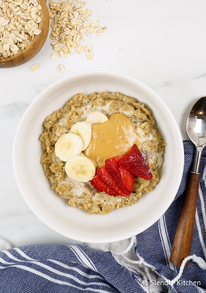 Microwave banana oatmeal in a bowl with peanut butter, sliced bananas, and strawberries.